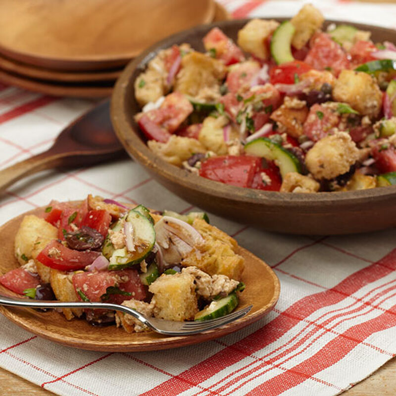 A bowl of panzanella salad consisting of bread, cucumber, red onion and tomato.